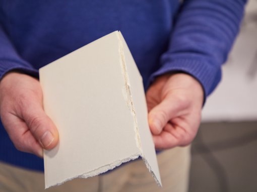 ein in den Händen glatt gebrochenes Stück Finnische Holzpappe