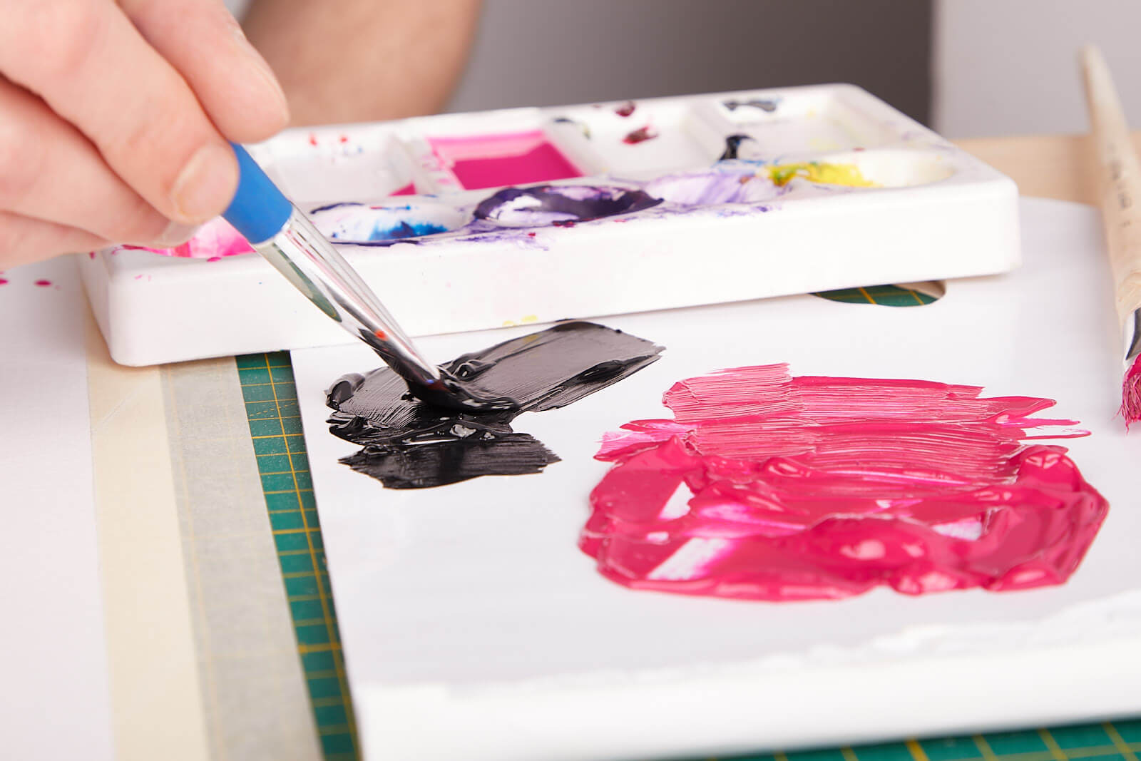 Acrylfarbe anrühren Auf einem Skizzenblock wird mit einem Pinsel schwarze Acrylfarbe zum Einstellen der Konsistenz angerührt.