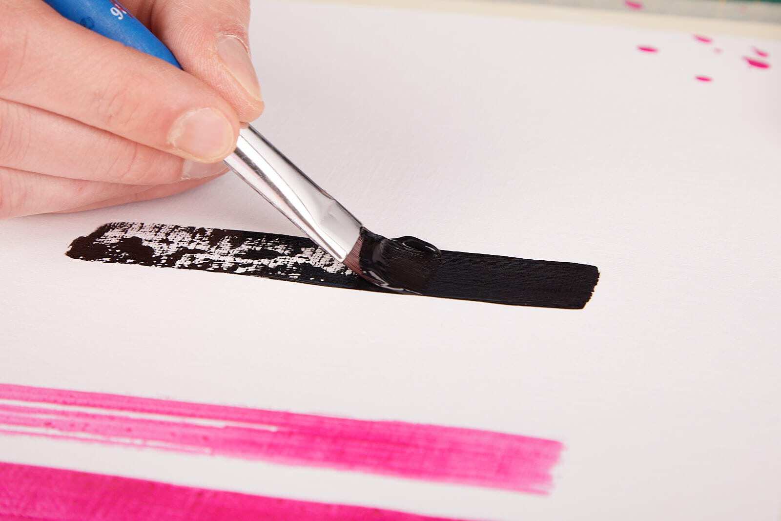 schwarzer Pinselstrich Acrylfarbe auf einem Papier wird mit einem Pinsel ein mittelbreiter, satt schwarzer Strich direkt auf einen zuvor nicht so satt aufgetragenen Strich gemalt.
