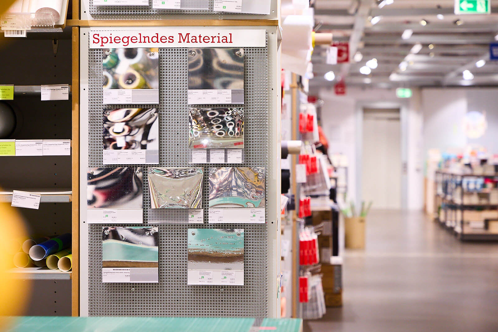 Ein Bild aus dem Modulor Ladengeschäft. Zu sehen ist die Präsentation von Mustern verschiedener Klebefolien. Die Musterstücke hängen nebeneinander an der Wand und sind bezeichnet.
