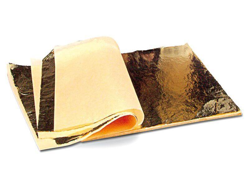 Ein kleiner Stapel von dünnen, gold-glänzenden Metallfolien liegt auf weißem Untergrund. Ein Teil der Metallblätter liegt halbiert umgeschlagen obenauf.