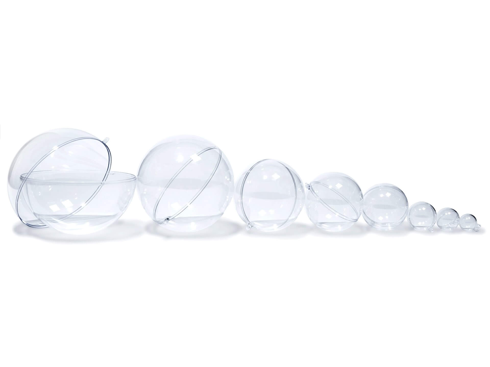 Polystyrol Kugeln Durchsichtige, zweiteilige Kugeln aus Polystyrol liegen der Größe nach sortiert nebeneinander. Die Kugeln bestehen immer aus zwei Hälften, die ineinander gesteckt werden können. Die fünf kleineren Kugeln sind zusammengesteckt, bilden also komplette Kugeln. Bei den drei größeren Durchmessern liegen die Halbkugeln offen ineinander da.