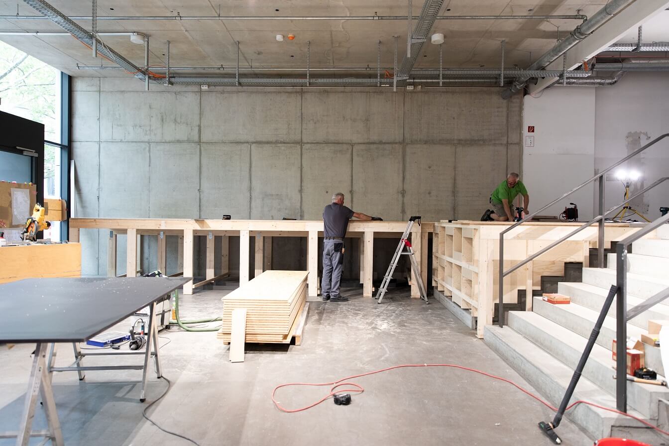 Ein Holz-Ständerwerk wird vor der zukünftigen Stiftewand aufgebaut. Es wird später dazu dienen, den Fußboden vor der Stitewand zu tragen. Es ist also die Unterkonstrultion eines großen Podests.