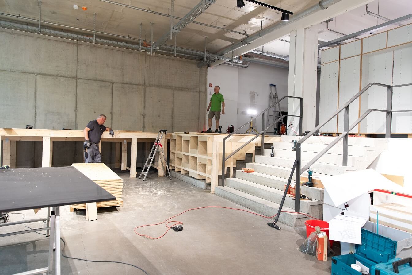 Das Holständerwerk für das Podest wurde auch auf die eine der drei Betontreppen, die in die Ladenerweiterung führen, gebaut. Hier ist es noch als Konstruktion unverkleidet zu sehen.